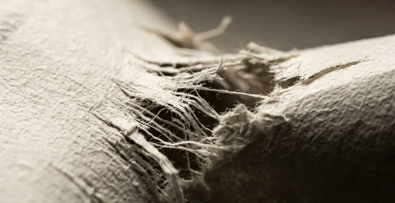 Vue macroscopique des fibres d'un document financier qui se déchire, symbolisant le fardeau d'une dette à vie.