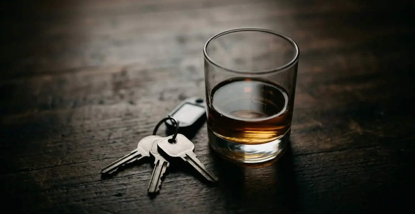 Clés de voiture posées à côté d'un verre d'alcool sur une table