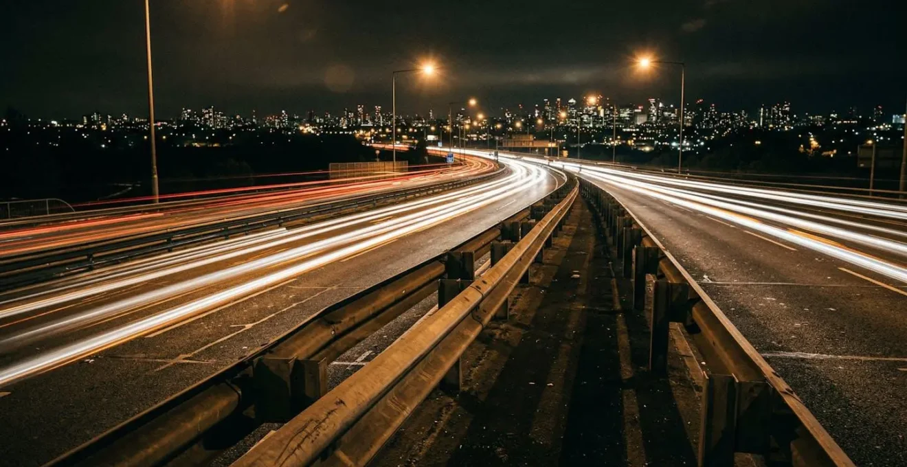 Vue large d'une autoroute la nuit avec circulation intense et barrières de sécurité illuminées.